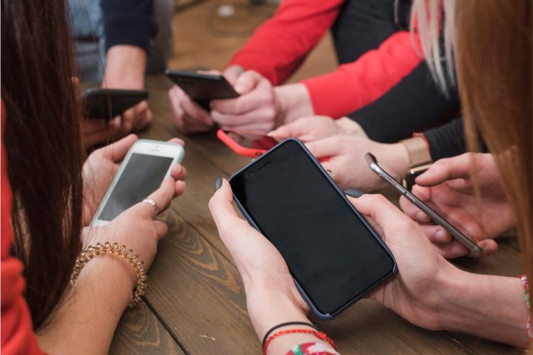 immagine di tanti smartphone tenuti in mano da un gruppo di ragazzi