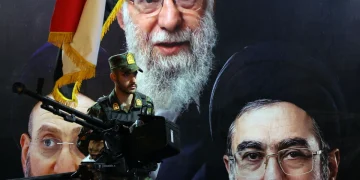 an-iranian-military-member-stands-guard-in-front-of-the-picture-of-late-iranian--1200x800.webp