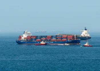 Grande nave portacontainer scortata da rimorchiatori nello stretto di Hormuz.