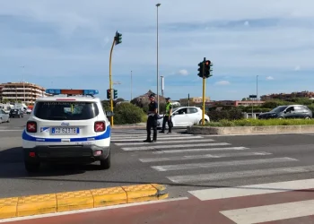 Agenti polizia locale regolano traffico, veicolo di pattuglia sullo sfondo