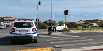 Agenti polizia locale regolano traffico, veicolo di pattuglia sullo sfondo