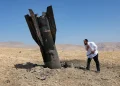 Uomo ebreo osserva inquieto detriti di missile balistico nel deserto.