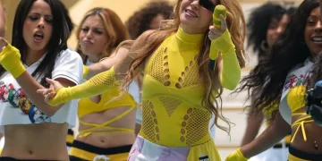 Shakira canta occhiali da sole sul palco con vestito giallo