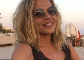 Patrizia Caselli sorride in spiaggia con occhiali da sole rotondi