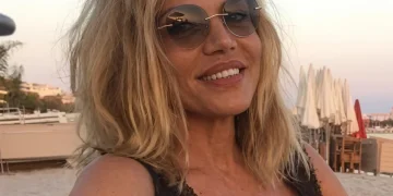 Patrizia Caselli sorride in spiaggia con occhiali da sole rotondi