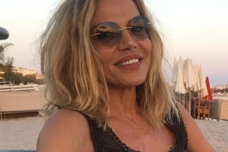 Patrizia Caselli sorride in spiaggia con occhiali da sole rotondi