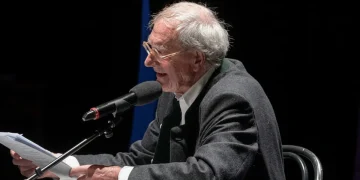 Romano Montroni legge documenti al microfono durante convegno