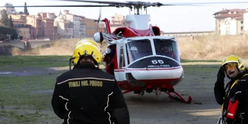 Vigili del Fuoco accanto elicottero in campo durante operazioni ricerca
