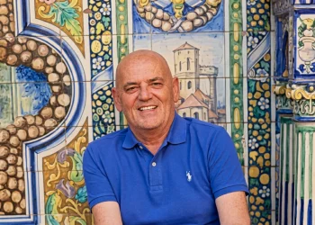 Stefano Addeo sorride in polo blu davanti a ceramiche decorate.