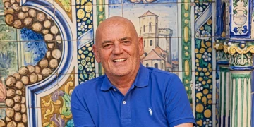 Stefano Addeo sorride in polo blu davanti a ceramiche decorate.