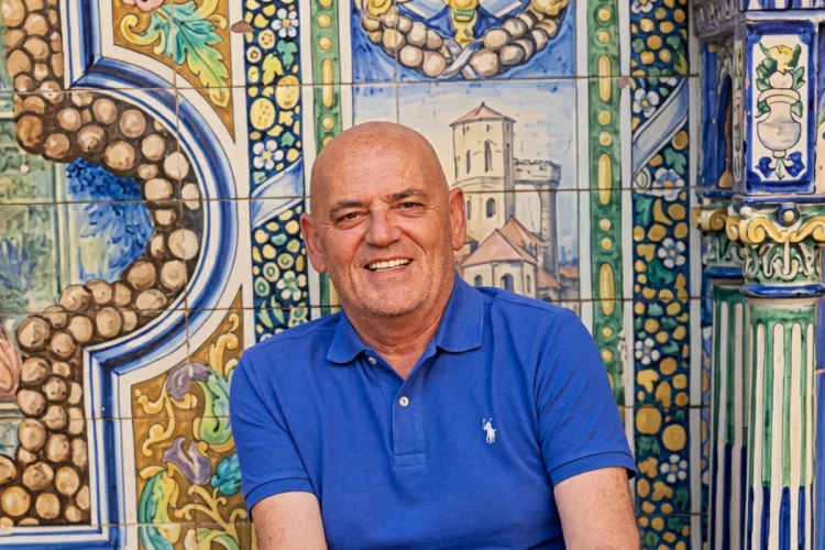 Stefano Addeo sorride in polo blu davanti a ceramiche decorate.