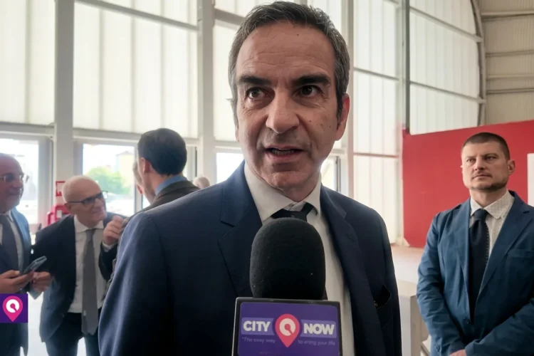 Uomo in giacca e cravatta parla al microfono "CITYNOW"
