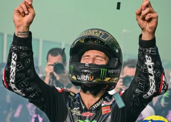 Fabio Quartararo alza le braccia, festeggiando la vittoria sul podio.
