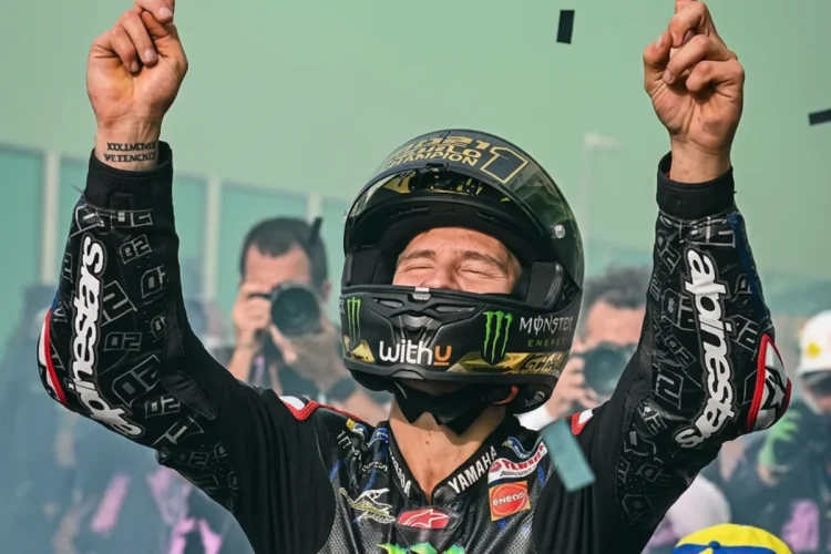 Fabio Quartararo alza le braccia, festeggiando la vittoria sul podio.