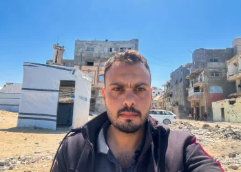Primo piano di Moumen Al-Natour a Gaza davanti a edifici distrutti