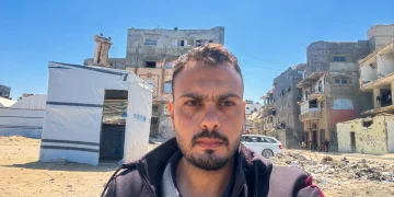 Primo piano di Moumen Al-Natour a Gaza davanti a edifici distrutti