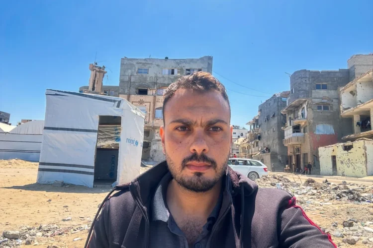 Primo piano di Moumen Al-Natour a Gaza davanti a edifici distrutti