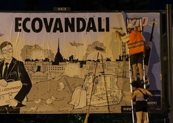 Attivisti coprono cartellone Leonardo con scritta ECOVANDALI a Torino.