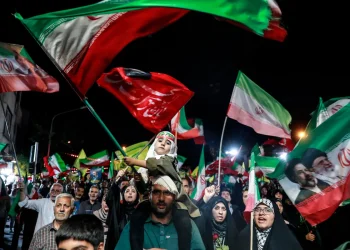 Folla di manifestanti iraniani con bandiere e ritratti dei leader