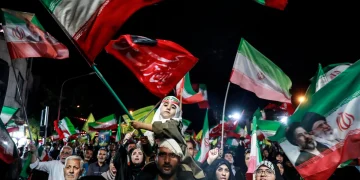 Folla di manifestanti iraniani con bandiere e ritratti dei leader