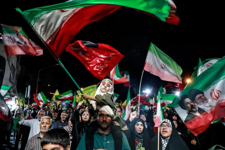 Folla di manifestanti iraniani con bandiere e ritratti dei leader
