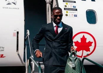 Ismaël Koné scende da un aereo in abito elegante con borsa