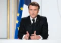 Emmanuel Macron parlante al podio con bandiera francese sullo sfondo