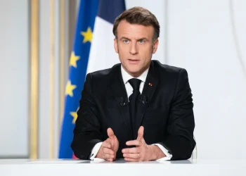 Emmanuel Macron parlante al podio con bandiera francese sullo sfondo