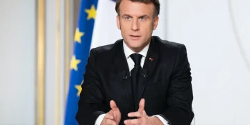 Emmanuel Macron parlante al podio con bandiera francese sullo sfondo