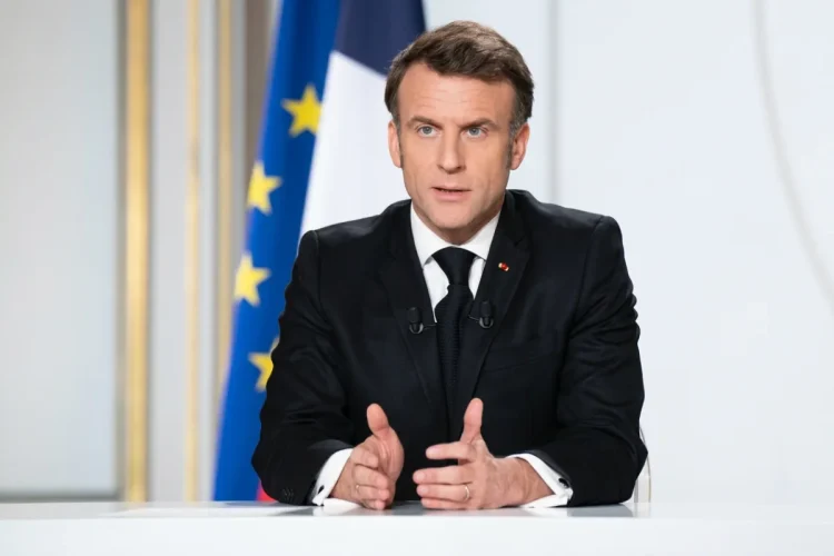 Emmanuel Macron parlante al podio con bandiera francese sullo sfondo