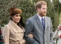 Meghan Markle e il Principe Harry sorridono camminando insieme all'aperto.