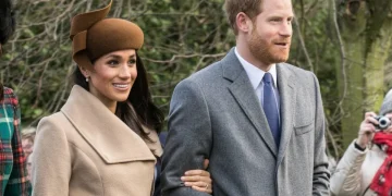 Meghan Markle e il Principe Harry sorridono camminando insieme all'aperto.