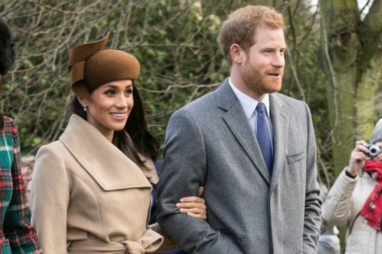 Meghan Markle e il Principe Harry sorridono camminando insieme all'aperto.