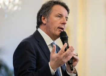 Matteo Renzi parla al microfono con un abito blu.