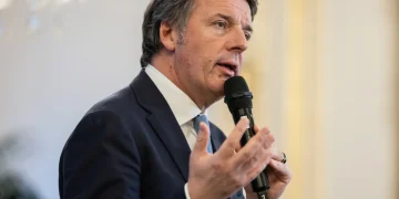 Matteo Renzi parla al microfono con un abito blu.
