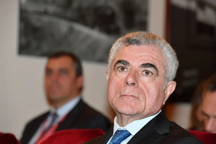 Mauro Moretti in primo piano con giacca e cravatta blu.