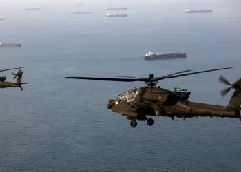 Elicotteri Apache militari sorvolano, a bassa quota, navi mercantili nello Stretto di Hormuz.