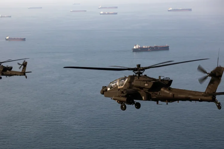Elicotteri Apache militari sorvolano, a bassa quota, navi mercantili nello Stretto di Hormuz.