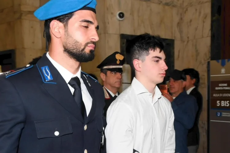 Ragazzo con camicia bianca scortato da un carabiniere in tribunale.
