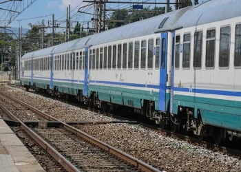 Treno passeggeri bianco e azzurro in una stazione ferroviaria.