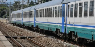 Treno passeggeri bianco e azzurro in una stazione ferroviaria.
