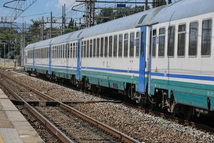 Treno passeggeri bianco e azzurro in una stazione ferroviaria.