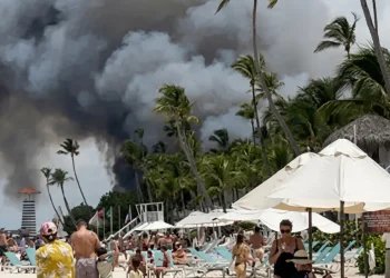 Fumo nero da un incendio su una spiaggia caraibica affollata