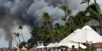 Fumo nero da un incendio su una spiaggia caraibica affollata