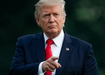 Donald Trump con cravatta rossa punta il dito in avanti