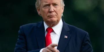 Donald Trump con cravatta rossa punta il dito in avanti