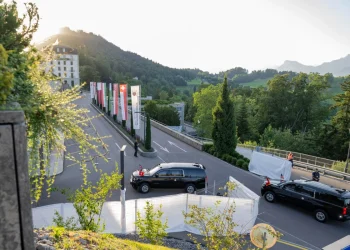 SUV nero con bandiere sventolanti vicino hotel in Svizzera