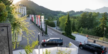 SUV nero con bandiere sventolanti vicino hotel in Svizzera