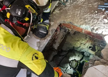 Vigile del fuoco italiano scava tra macerie con una torcia