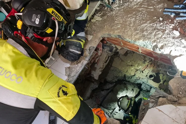 Vigile del fuoco italiano scava tra macerie con una torcia